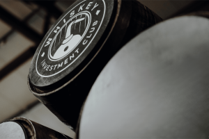 A cask with a whiskey invest logo on top of a black, blank cask
